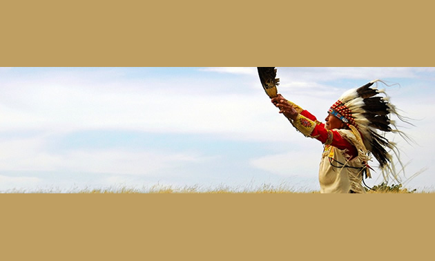 Elderly First Nations man in feather headdress and beaded leather clothing