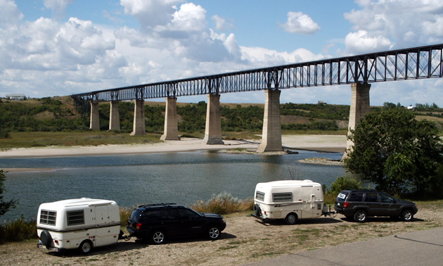 Campers parked by the river looking out toward the SkyTrail Bridge. 