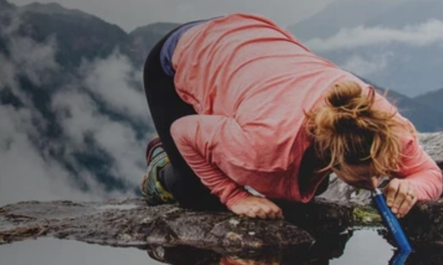 person drinking through a Lifestraw