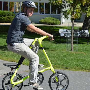 Spencer Shellborn riding a Strida Bike in a park.