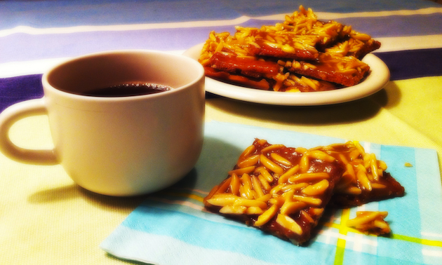 Cup of tea and shiny squares of baking on a napkin.