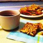 Cup of tea and shiny squares of baking on a napkin.