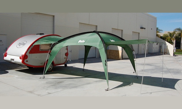A green Cottonwood XLT shade shelter set up to join a teardrop trailer. 