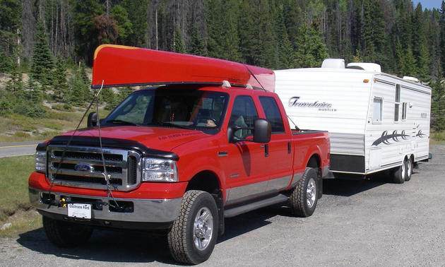 This photo shows the author's first RV, a trailer, being pulled by a red pick-up truck.