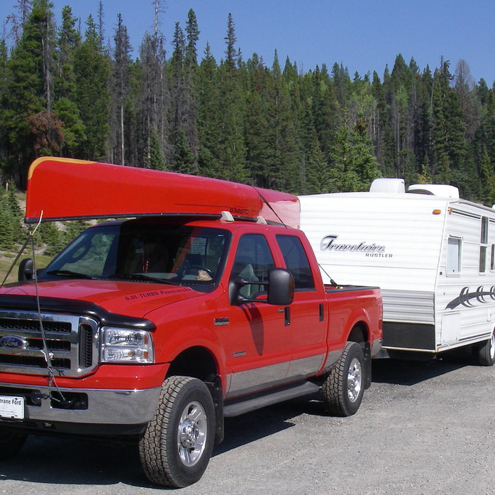 This photo shows the author's first RV, a trailer, being pulled by a red pick-up truck.