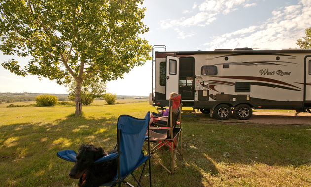 A person is sitting in a camp chair and eyeing the view in North Battleford, Saskatchewan, with an RV in the background.
