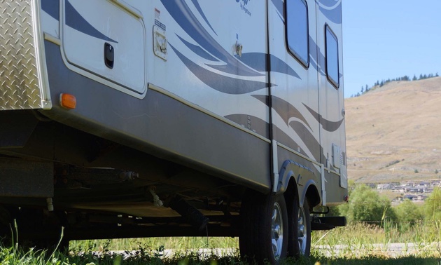 The bottom half of a trailer in a field, showing the back tires. 