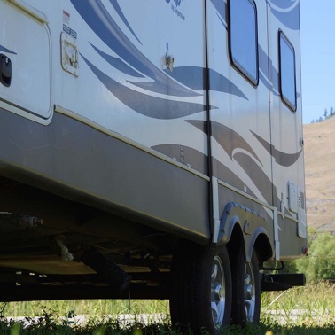 The bottom half of a trailer in a field, showing the back tires. 