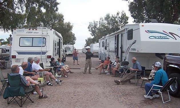 people sitting on lawn chairs in front of their RVs