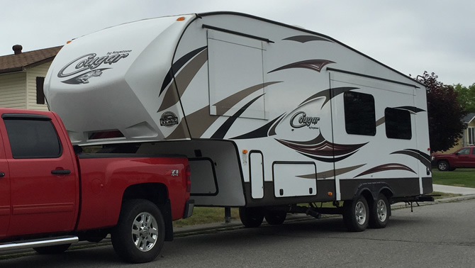 Picture of red truck towing fifth wheel trailer. 