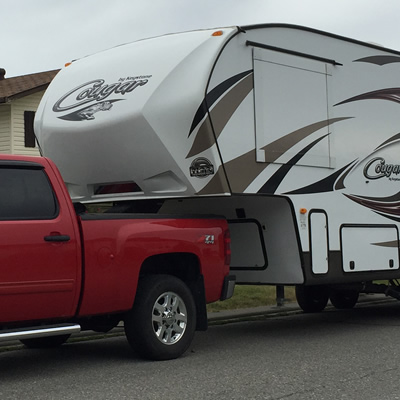 Picture of red truck towing fifth wheel trailer. 