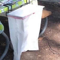 A Trash-Ease bag attached to a picnic table.