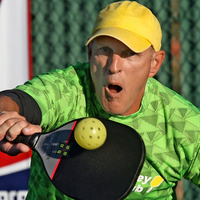 Pickleball player wearing yellow ball cap. 