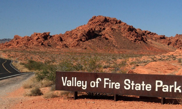 A photo of the Valley of Fire State Park sign with a red mountain in the background.