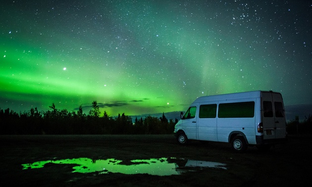 Ronn Murray's 8 passenger van with the aurora lights showing behind it.