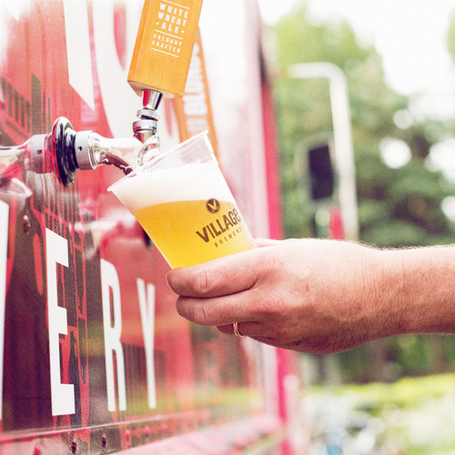 A man is filling a glass of beer from a beer tap at the Village Brewery.