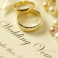 Photo of two wedding rings on top of paper with vows written on. 