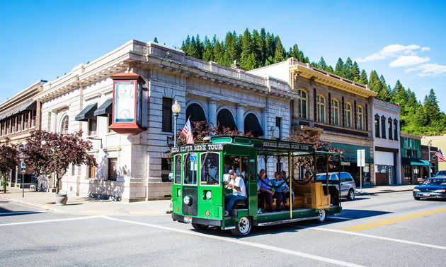 A green tour bus rides through downtown Wallace, the historic mining hub of Idaho.