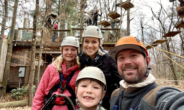 Family together with helmets on, going ziplining