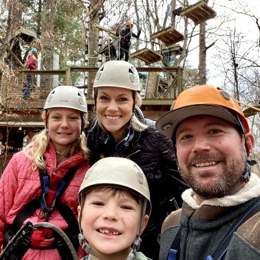 Family together with helmets on, going ziplining