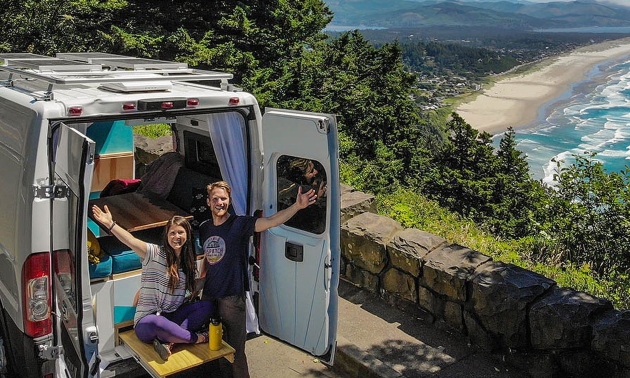 People at the back of their campervan, looking jubilant