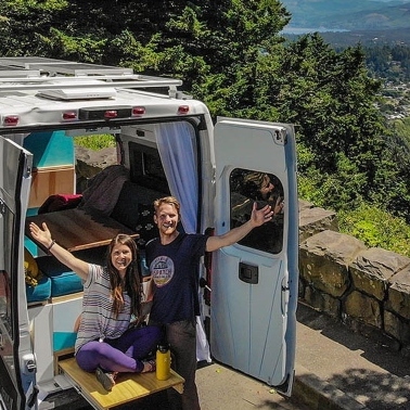 People at the back of their campervan, looking jubilant