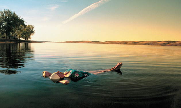 A woman floating in the minerals waters of Manitou Lake at sunset.