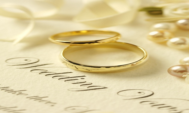 Photo of two wedding rings on top of paper with vows written on. 