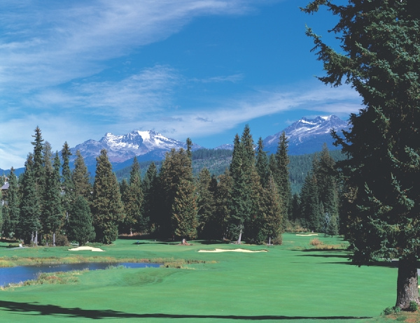 Scenic picture of the golf course in the forground, trees, mountains and ski in the background.