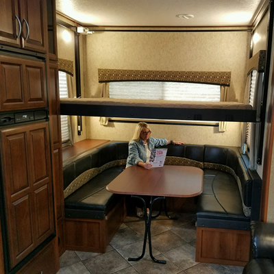 Picture of inside of RV, with woman sitting at table. 