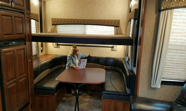 Picture of inside of RV, with woman sitting at table. 