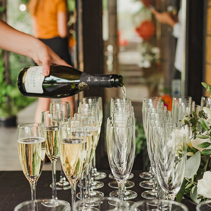 person pouring wine into glasses