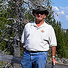 man standing on a bridge near a riverbank